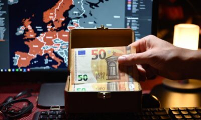 🎨 Portada Sugerida (16:9) Descripción: Un plano detalle de una mano guardando dos billetes de 50 euros dentro de una caja metálica pequeña o un cajón de madera. Al fondo, la pantalla de una computadora muestra un mapa de Europa con zonas de calor. Estética de sobriedad y realismo, con luz de hogar nocturna. Sin texto.
