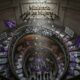 Editorial news illustration about women's rights policies being dismantled in Argentina, symbolic scene: a closed government building with the sign "Ministerio de las Mujeres" being dismantled, purple feminist flags and protest signs in the foreground, women silhouettes marching on March 8, dramatic lighting, newspaper cover style, political illustration, realistic, cinematic, high detail,