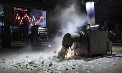 A cinematic wide shot of a massive, modern automated currency printing facility in Buenos Aires at night, in 16:9 aspect ratio. The printing presses are stopped and dark. In the foreground, a massive industrial vacuum-like machine, labeled with a subtle 'BCRA' logo, is actively sucking up piles of physical Argentine peso bills from the floor. The air is thick with dust and static electricity. Through a large window, a digital screen displays a volatile red graph showing 'IPC MARZO: 3.4%'. High-resolution cinematic photography, natural lighting from the machines, moody atmosphere, emphasis on the scale of the currency removal, no text.