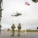 Soldados observan un helicóptero junto a la bandera de Groenlandia