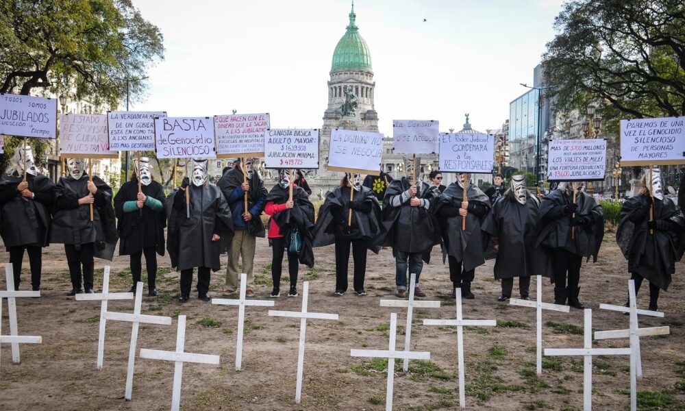 Manifestantes con túnicas negras y máscaras junto a cruces blancas frente al Congreso Nacional