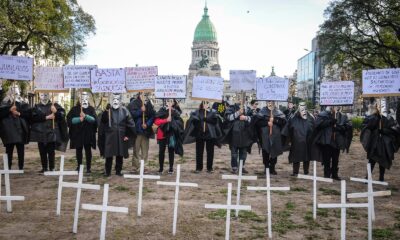Manifestantes con túnicas negras y máscaras junto a cruces blancas frente al Congreso Nacional