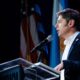 Axel Kicillof habla en un atril con banderas de Argentina, Estados Unidos y Brasil, sobre su viaje a Nueva York