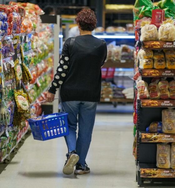 Una mujer camina por el pasillo de un supermercado con un canasto de compras, en el marco del dato de inflación de septiembre