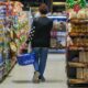 Una mujer camina por el pasillo de un supermercado con un canasto de compras, en el marco del dato de inflación de septiembre