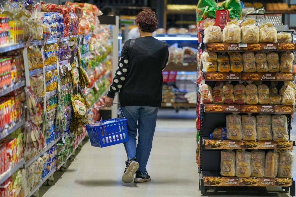 Una mujer camina por el pasillo de un supermercado con un canasto de compras, en el marco del dato de inflación de septiembre